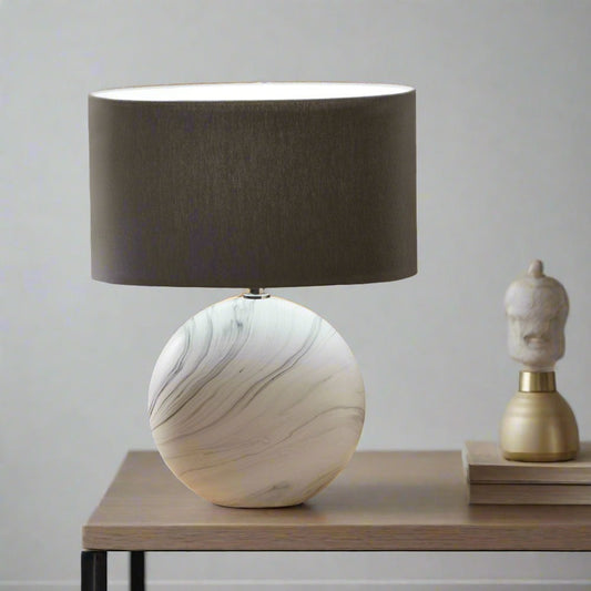 Table lamp with marble base and dark shade on a wooden surface