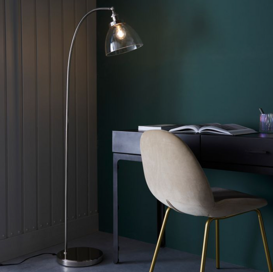 Illuminate your living space with timeless sophistication using this modern bright nickel &amp; clear glass floor lamp. Designed with a gracefully arched steel frame and a sleek dome-shaped glass shade, this lamp provides a perfect blend of modern and vintage aesthetics. Ideal for reading nooks, living rooms, and office spaces, it casts a soft and ambient glow, enhancing the warmth of your interiors.
